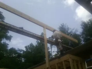 Carpenter setting a ridge beam over a new addition frame — Ice Dam Removal by Roofing Brothers in Granville